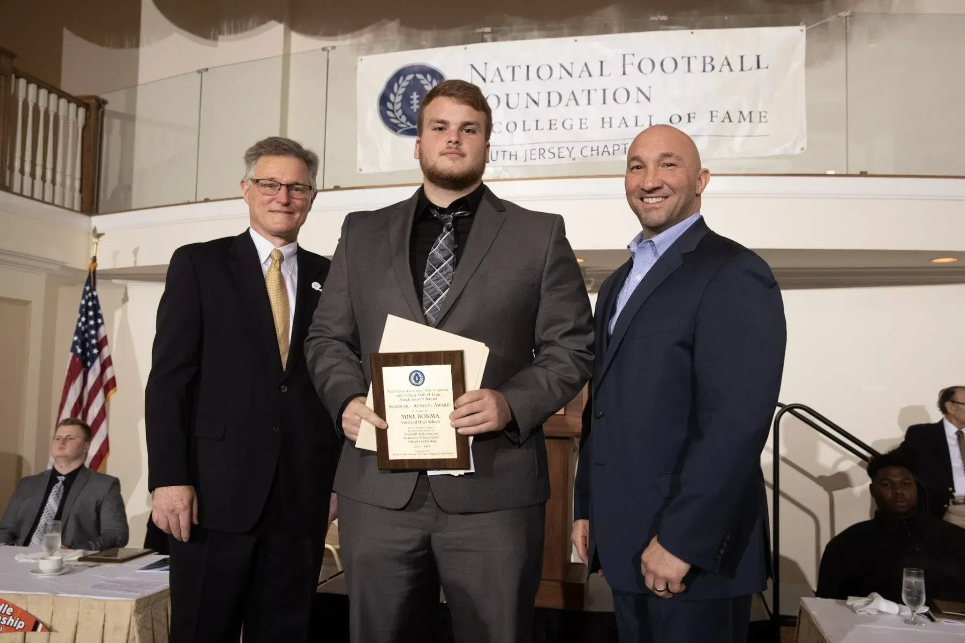 a man in a suit and tie is holding a certificate