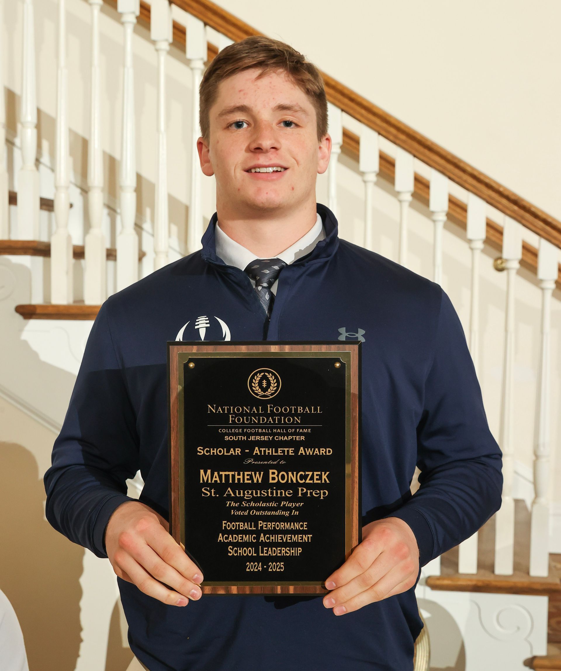 matthew bonczek of st. augustine high school holding an awards plaque