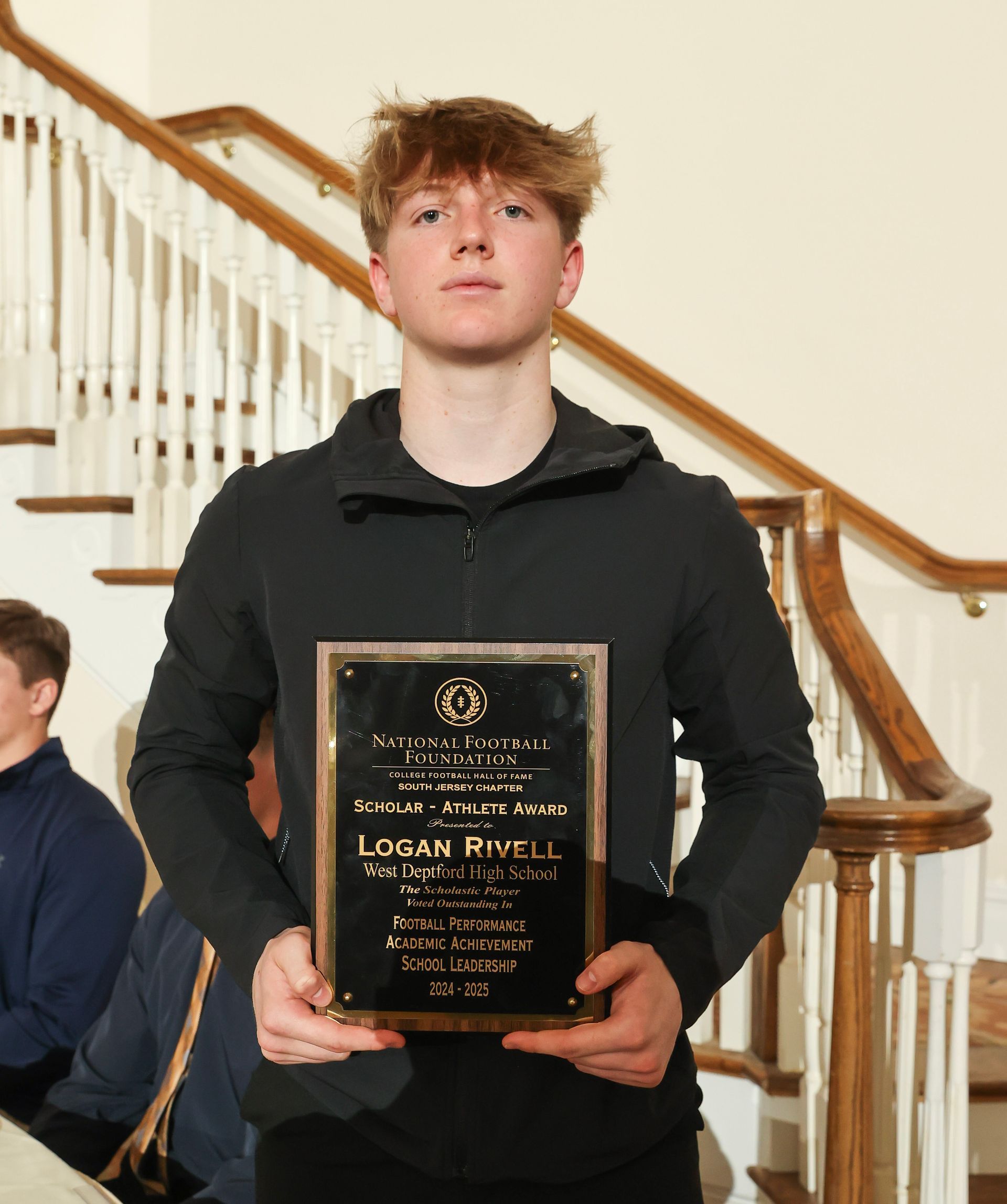 logan rivell of west deptford high school holding an awards plaque