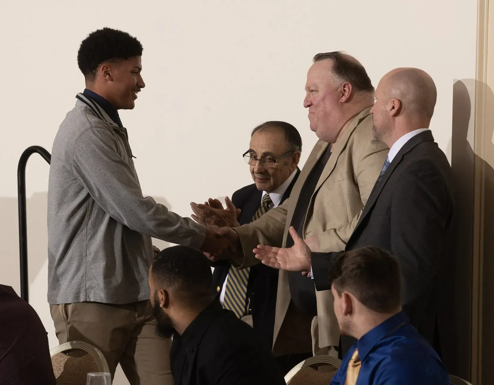 a group of men are shaking hands in a room