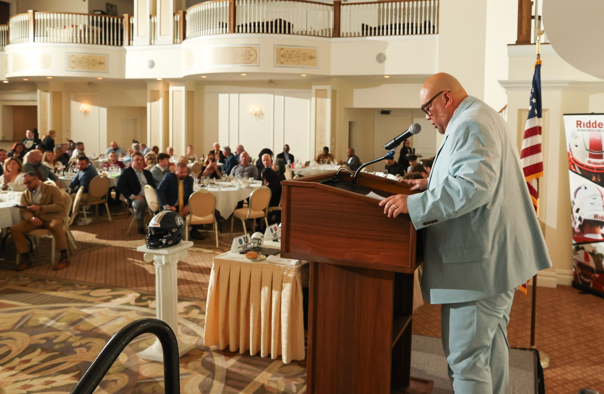 A man in a suit is giving a speech at a podium