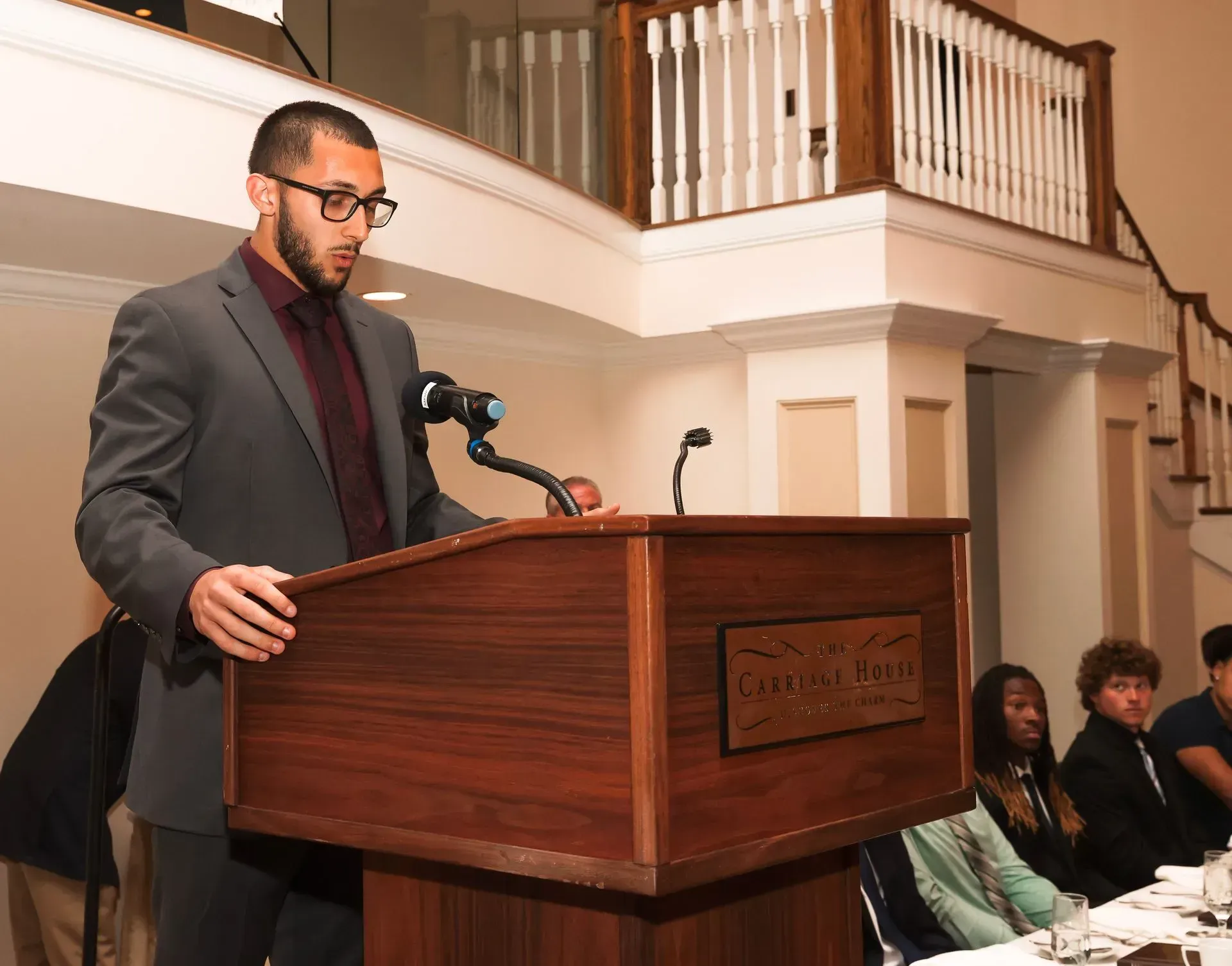 a man in a suit stands at a podium with a sign that says castle point