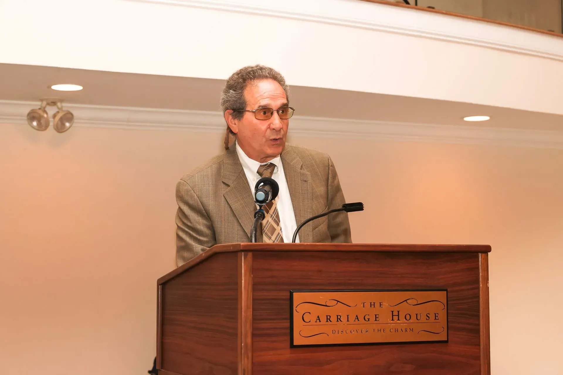 a man stands at a podium with a sign on it that says carolina inn