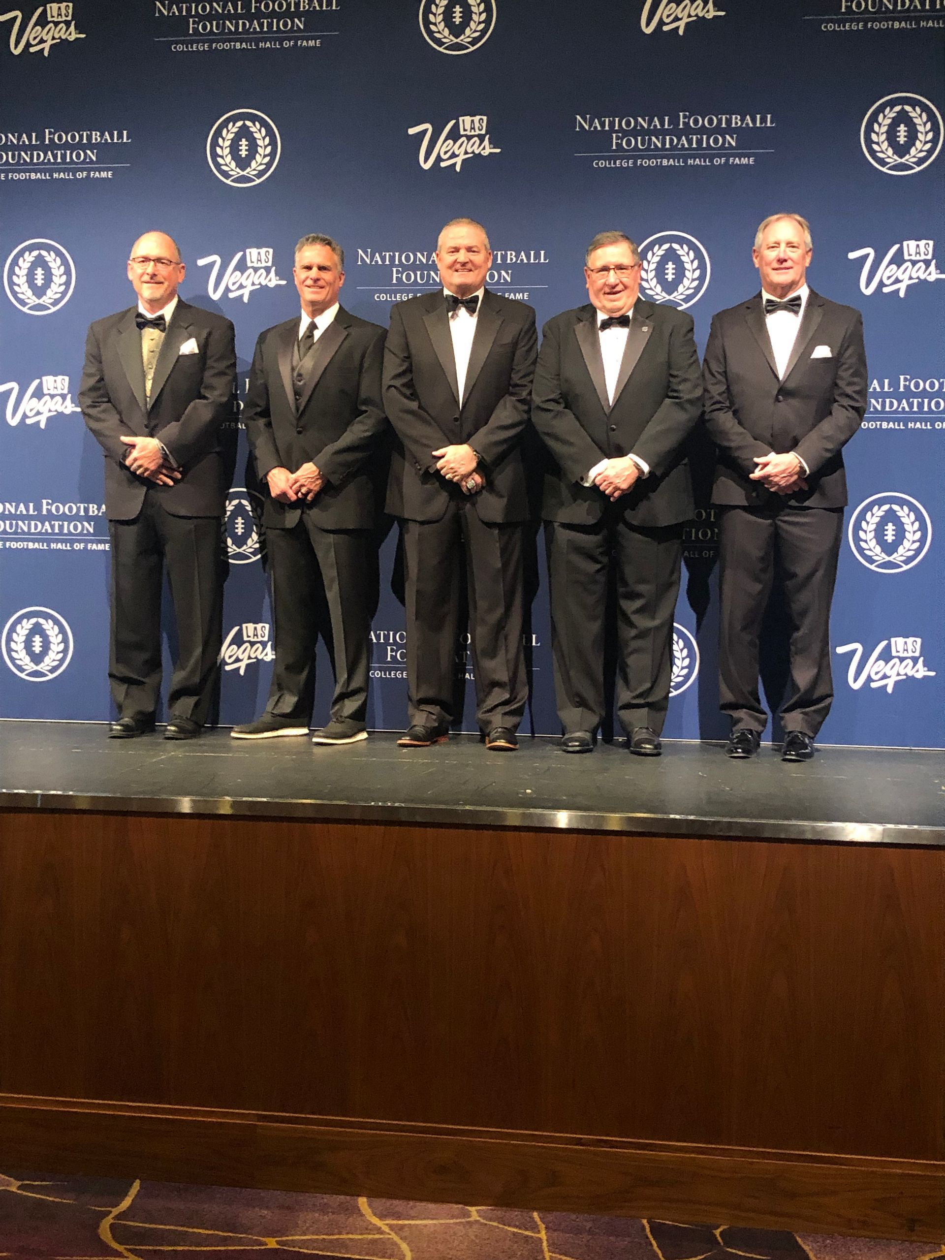a group of men in tuxedos are standing on a stage