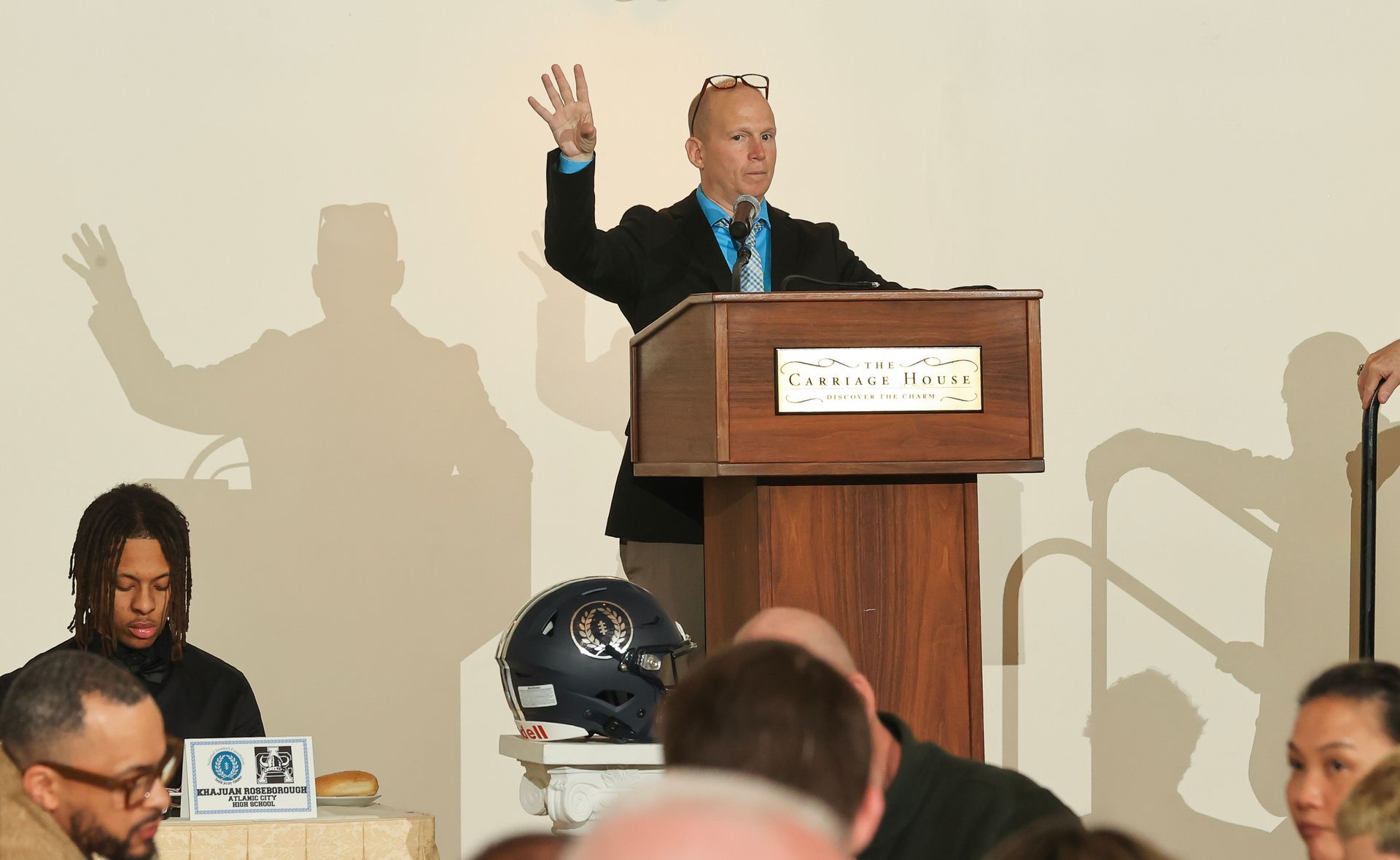 A man stands at a podium with his hand in the air