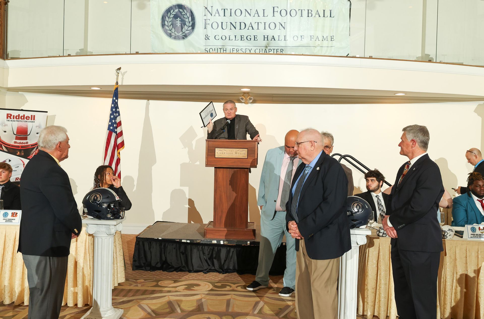 A man stands at a podium in front of a sign that says national football foundation
