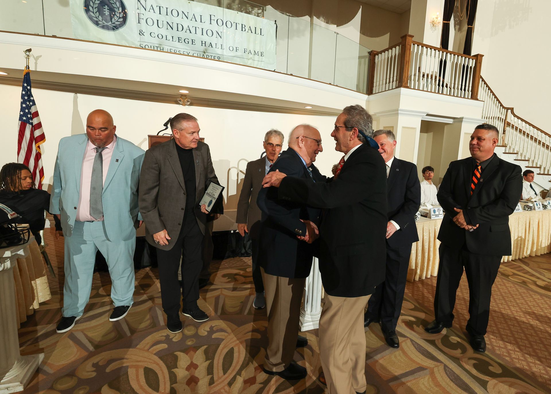 A group of men are standing in front of a sign that says national football foundation