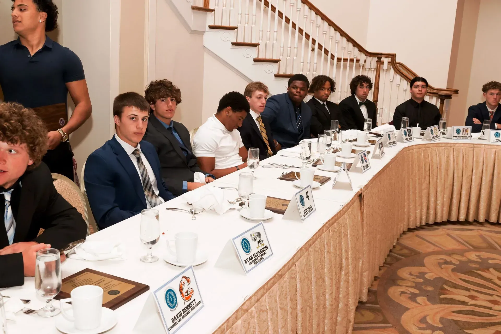 a group of young men are sitting at a long table