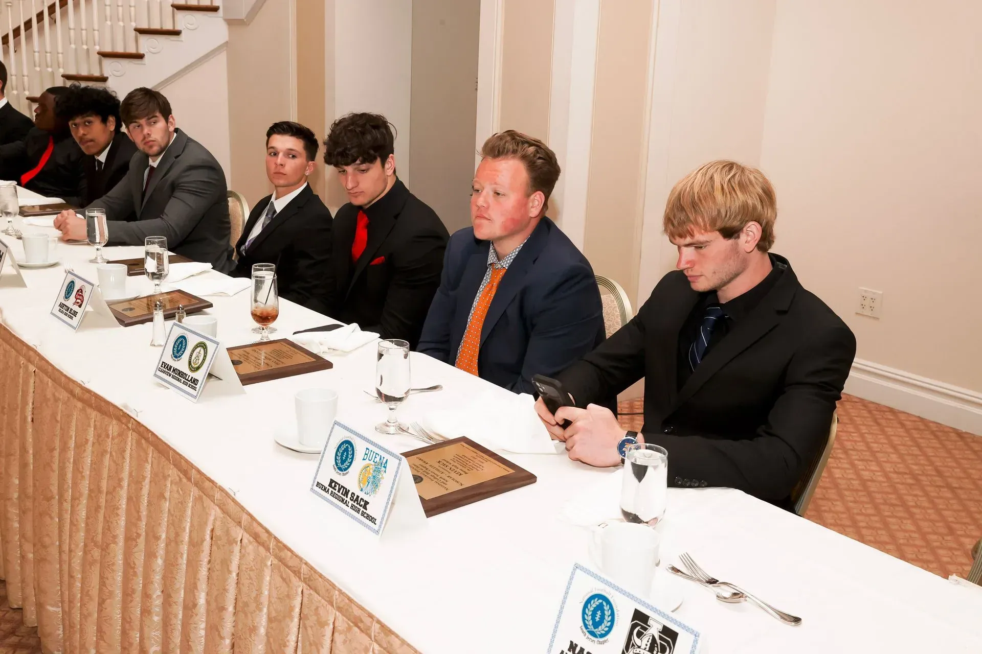 a group of men are sitting at a long table with a sign that says ' a ' on it