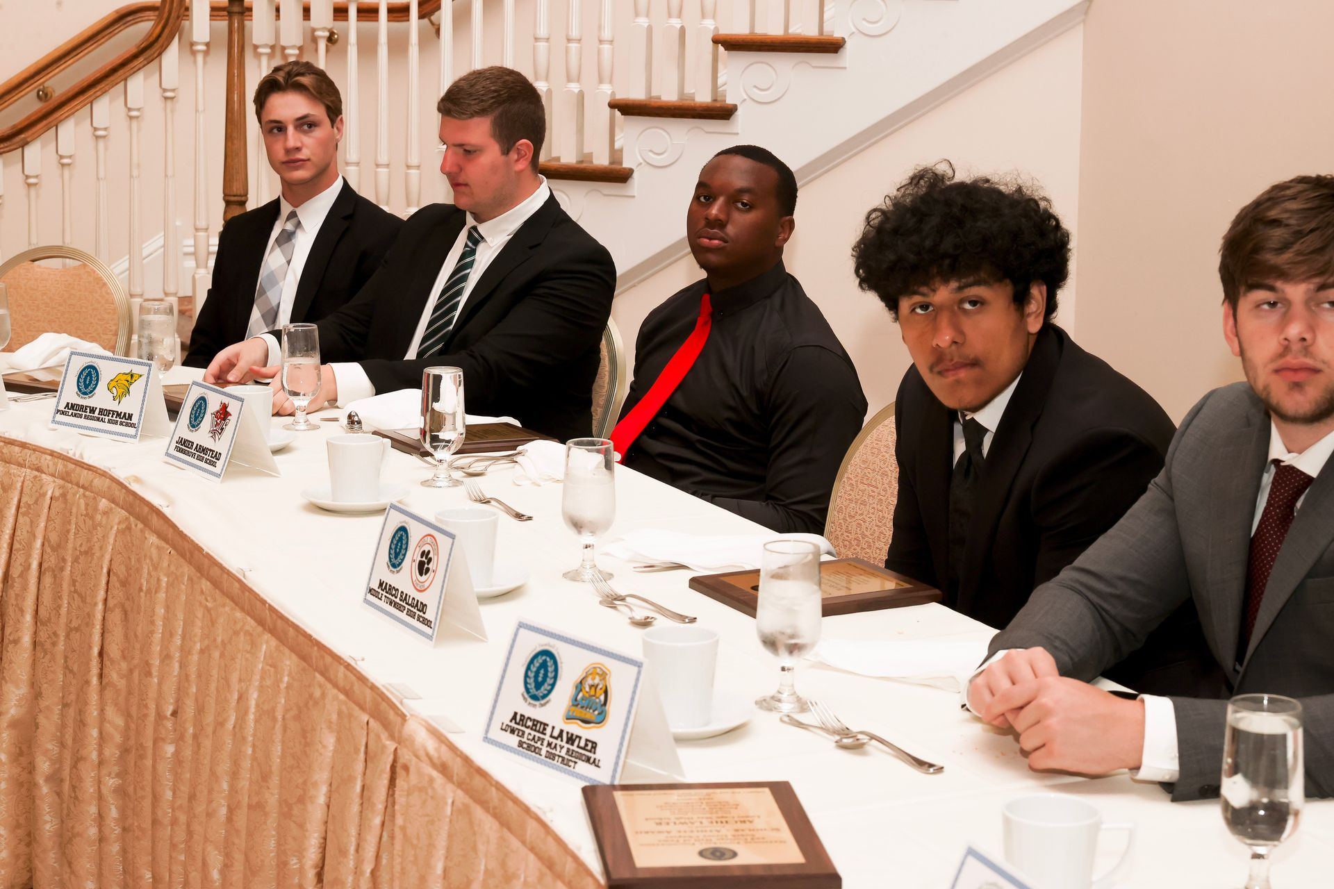 a group of men are sitting at a long table with a sign that says ' a ' on it