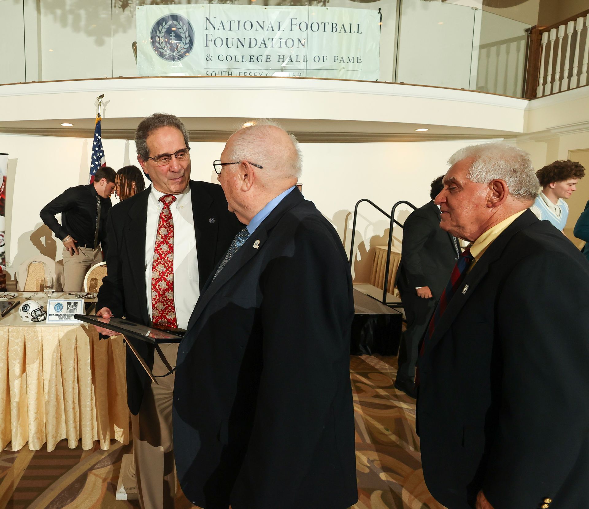 A group of men standing in front of a sign that says national football foundation