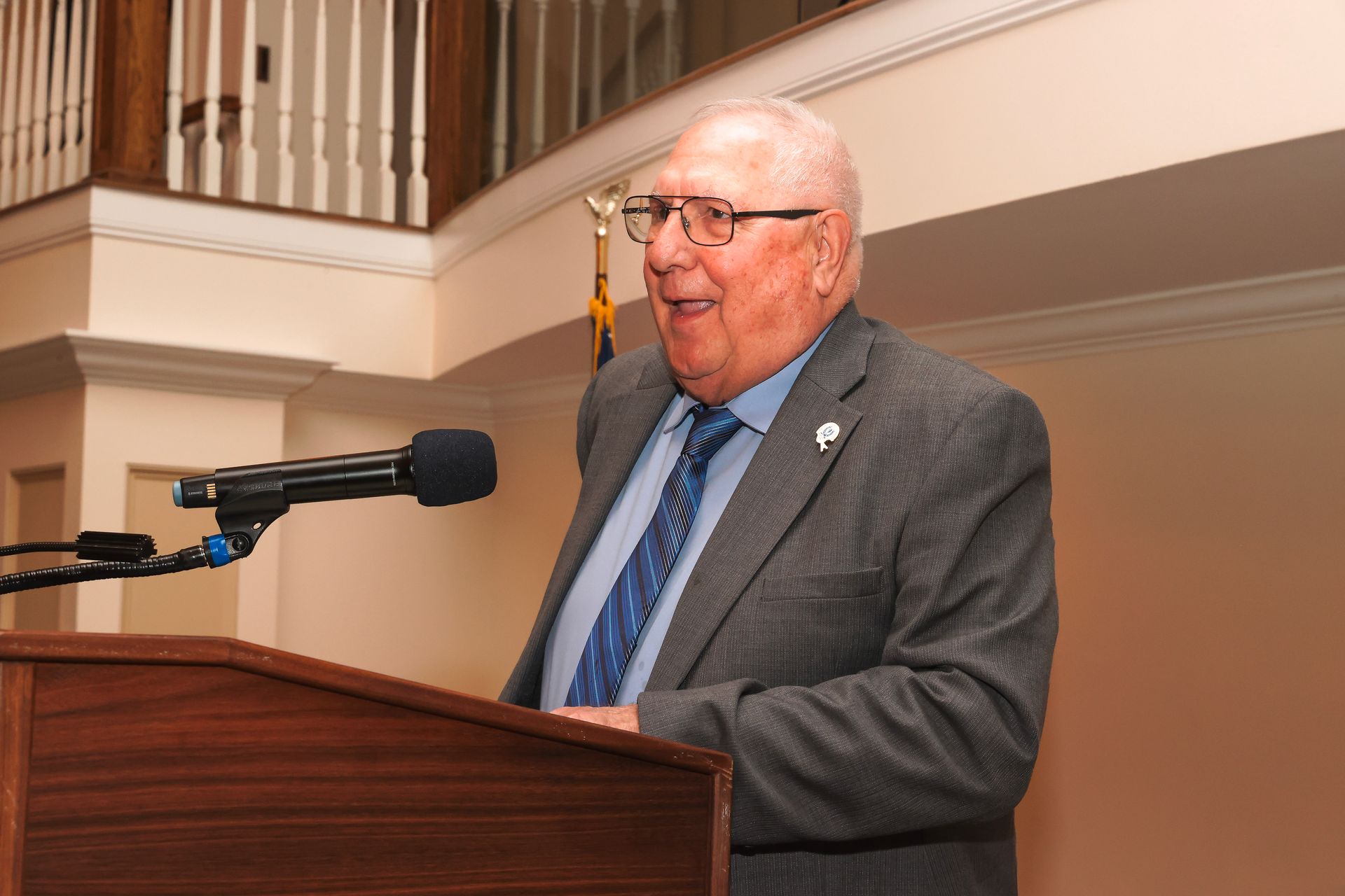 a man in a suit and tie is speaking into a microphone