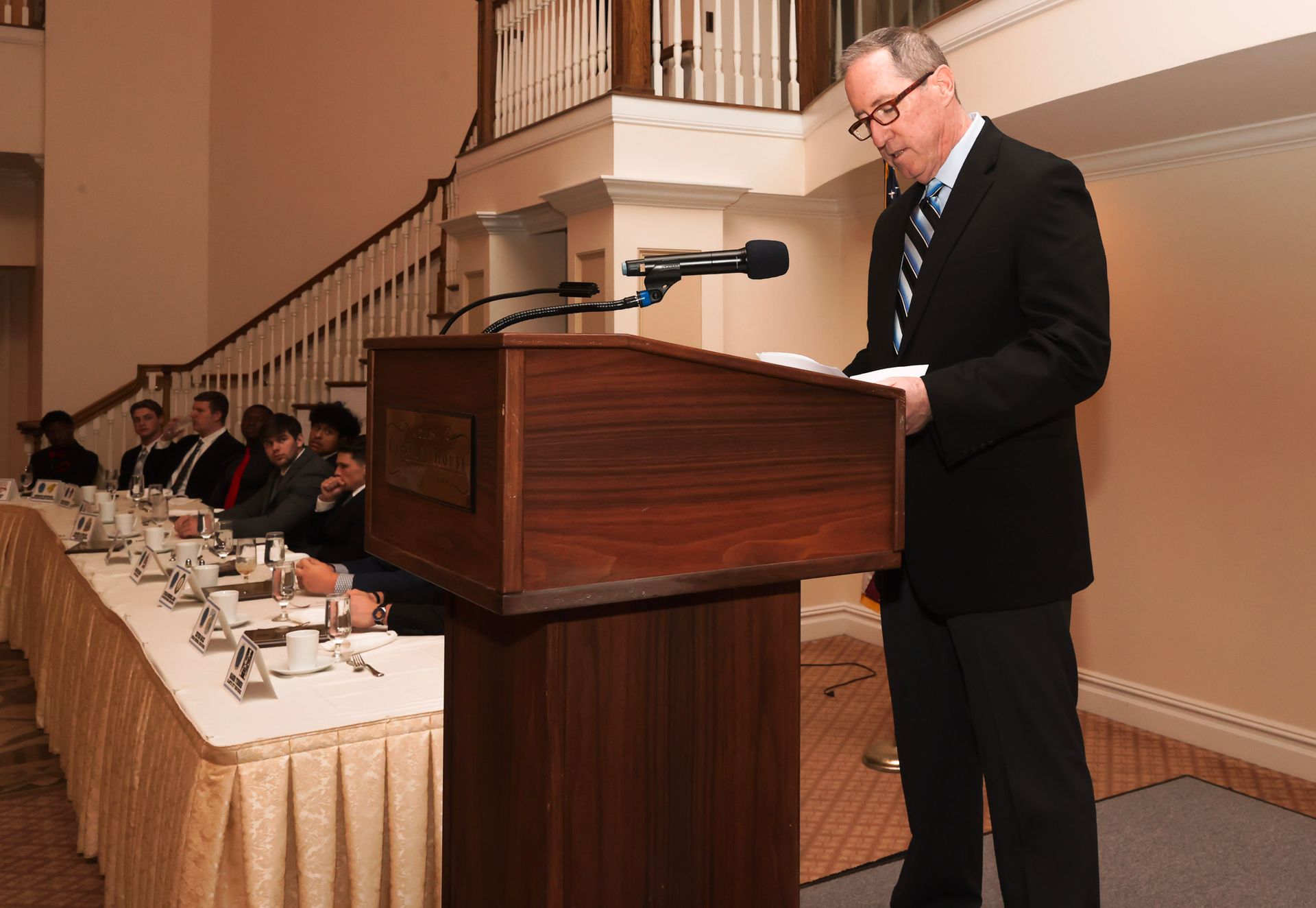 a man in a suit stands at a podium giving a speech