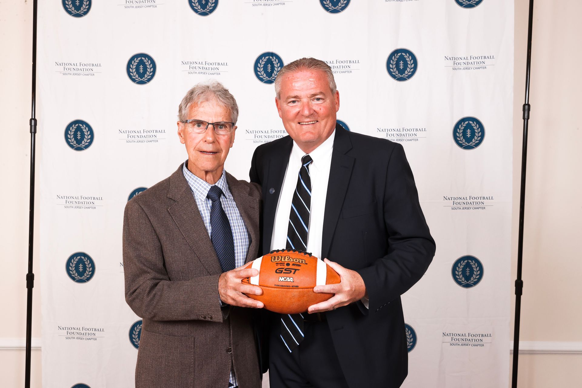 two men standing next to each other holding a football