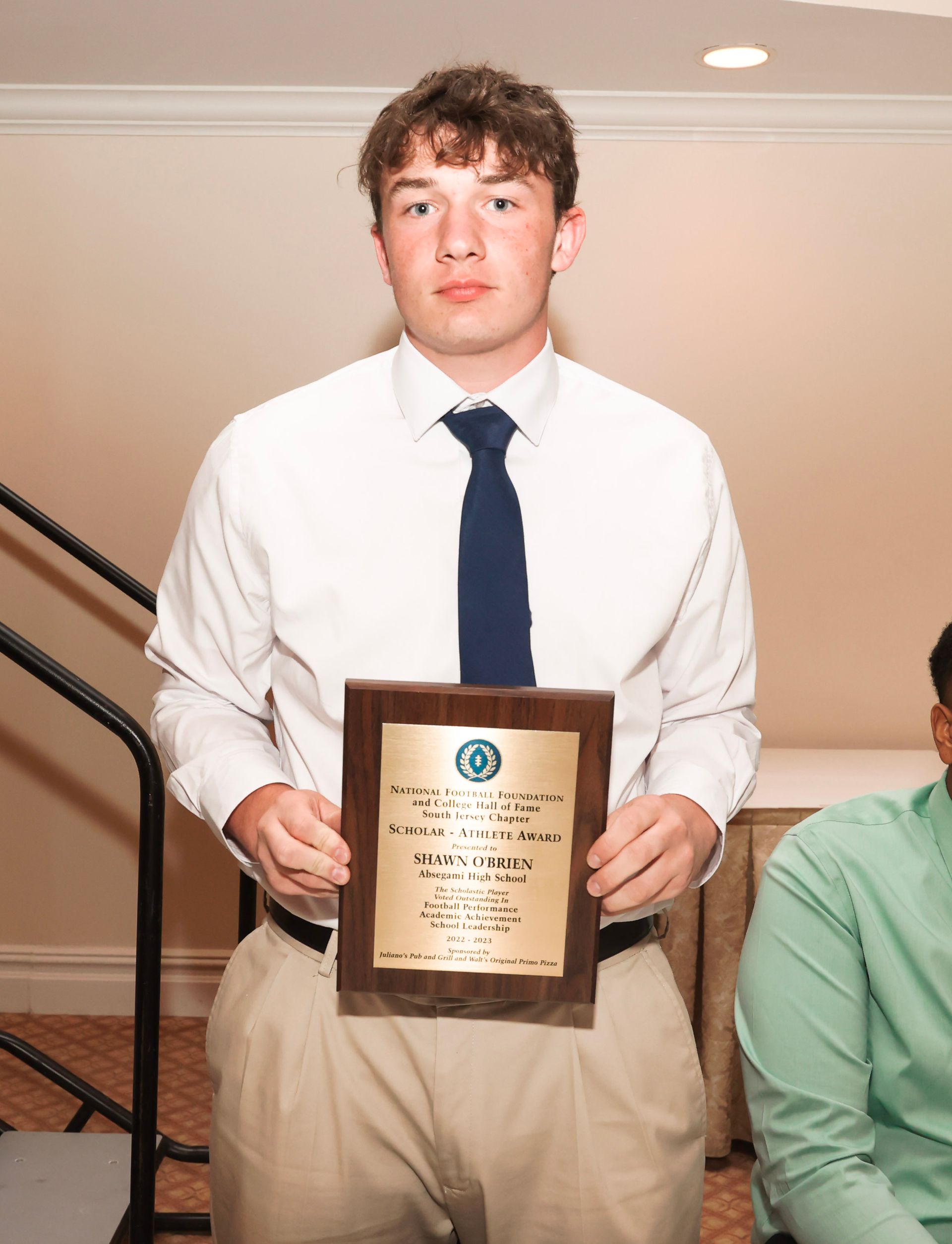 a young man in a white shirt and tie is holding a plaque