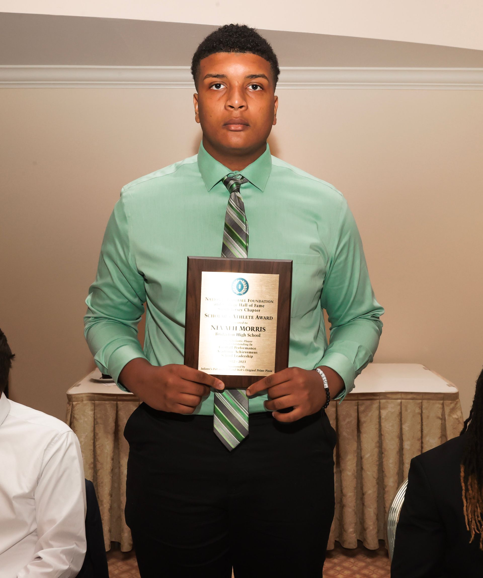 a man in a green shirt and tie is holding a plaque