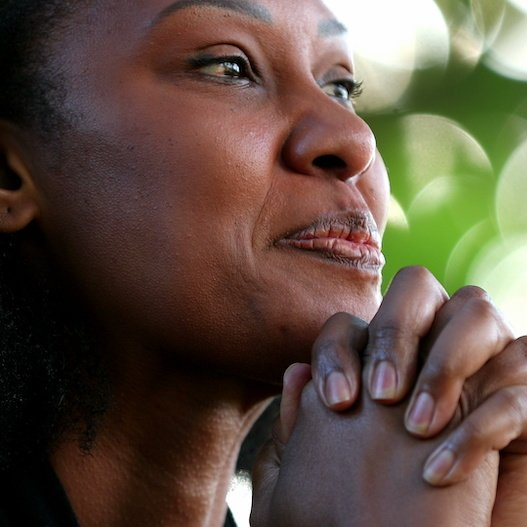 African American woman looking into the distance with folded hands