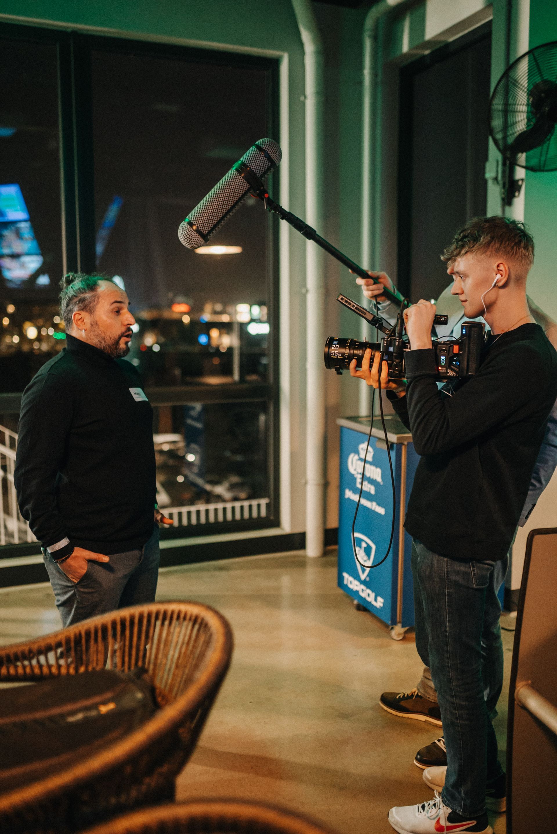 Ein Mann wird in einem Innenraum mit Kamera und Mikrofonangel gefilmt. Nachtszene, grüne Beleuchtung.