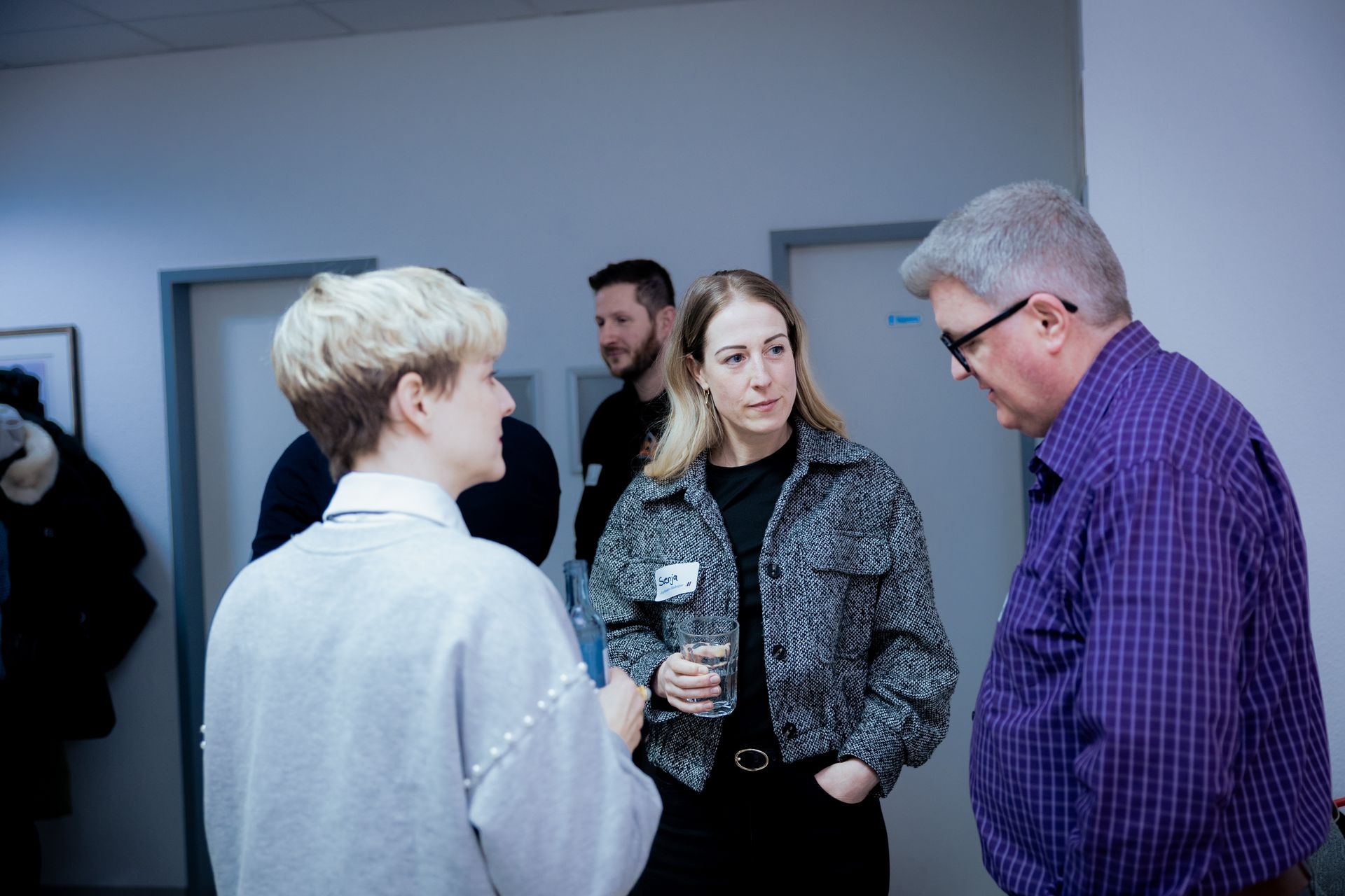 Zwei Männer, einer in einem roten, der andere in einem cremefarbenen Pullover, zeigen den Daumen nach oben. 