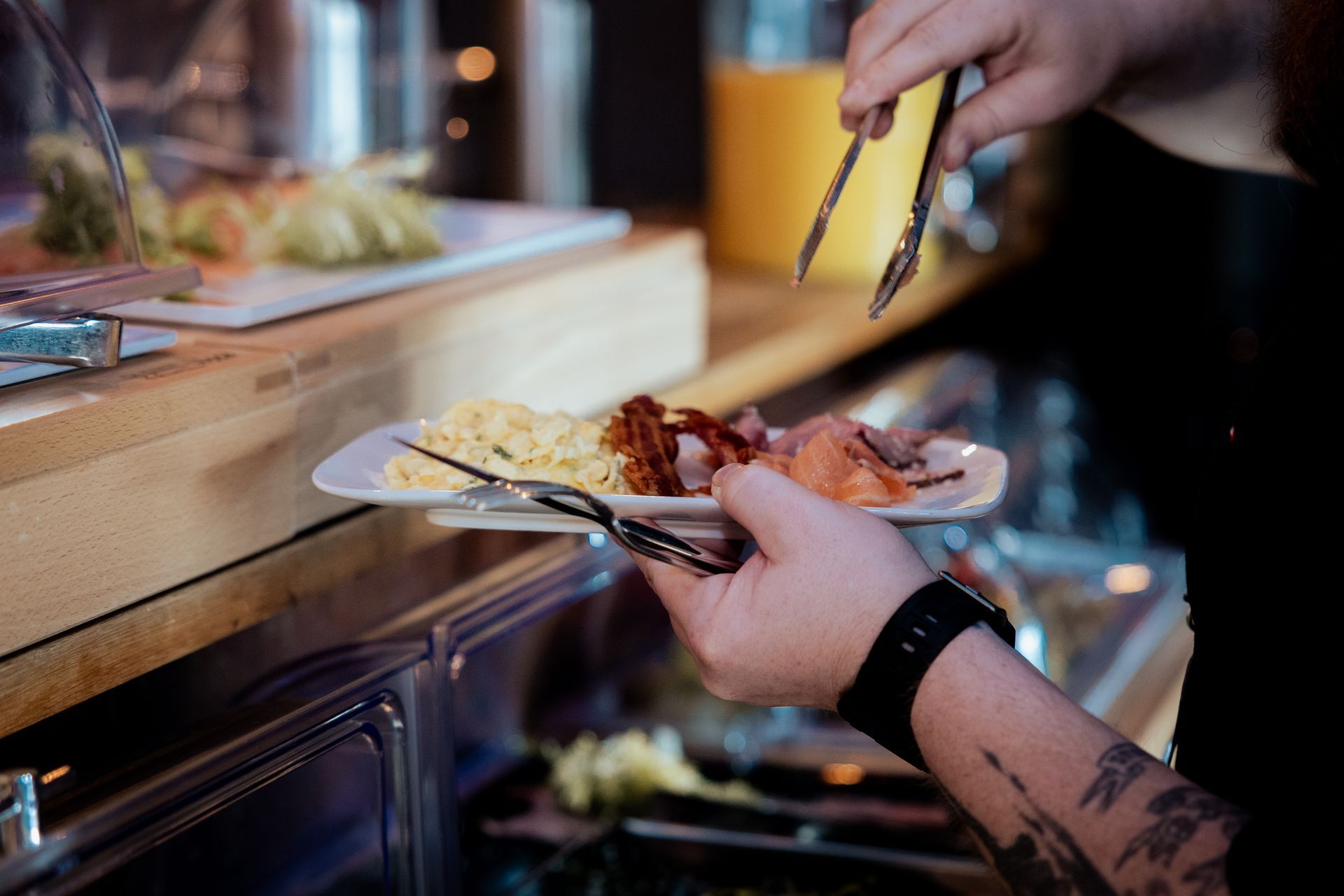 Zwei Männer, einer in einem roten, der andere in einem cremefarbenen Pullover, zeigen den Daumen nach oben. 