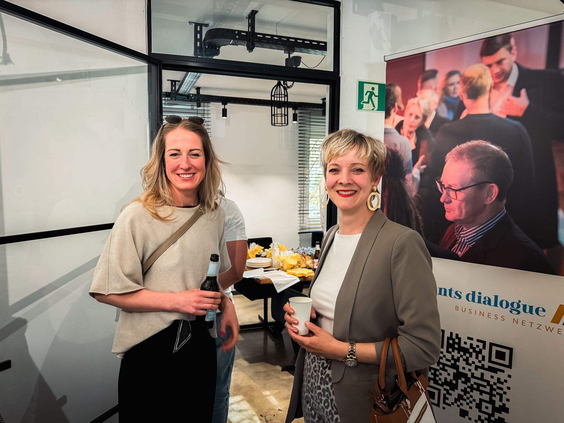 Zwei Männer, einer in einem roten, der andere in einem cremefarbenen Pullover, zeigen den Daumen nach oben. 