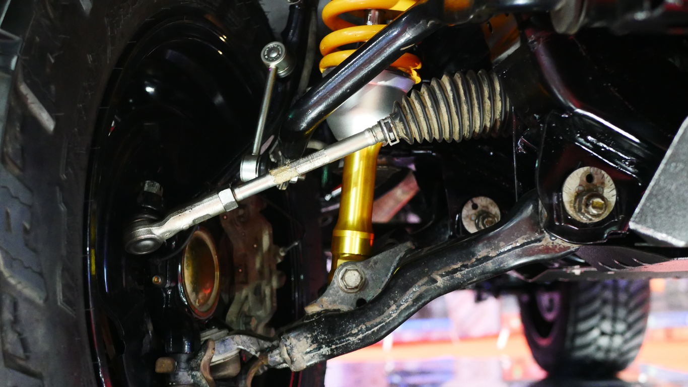 Close-up of a vehicle's suspension system, showing the shock absorber, steering components, and wheel hub.