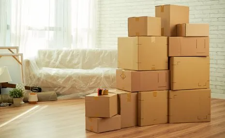 A pile of cardboard boxes stacked on top of each other in a living room.