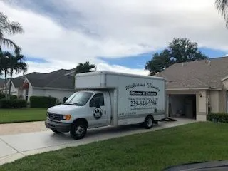 A white moving truck is parked in front of a house.