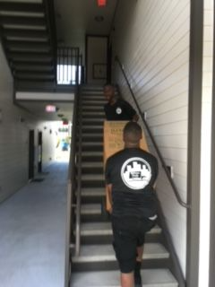 Two men are carrying a box up a set of stairs.