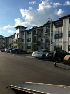 A row of cars are parked in front of a large apartment building