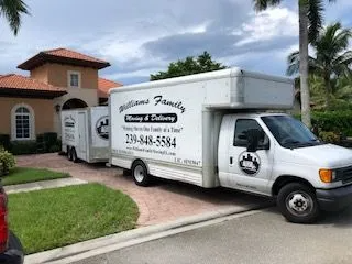 Two moving trucks are parked in front of a house.