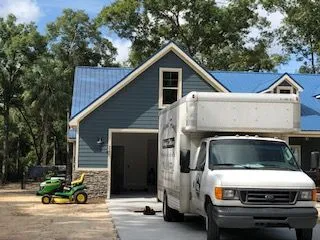 A white van is parked in front of a blue house.