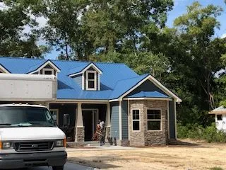 A white van is parked in front of a house with a blue roof.