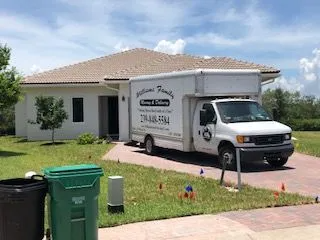 A white moving truck is parked in front of a house.