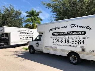 Two moving trucks are parked next to each other in a driveway.
