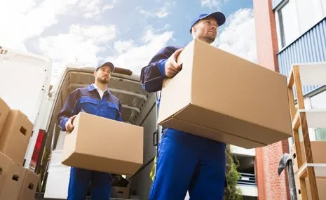 Two movers are carrying boxes out of a van.