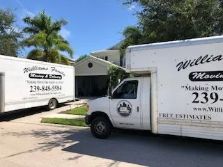 Two moving trucks are parked in front of a house.