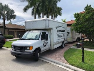 A white moving truck is parked in front of a house.