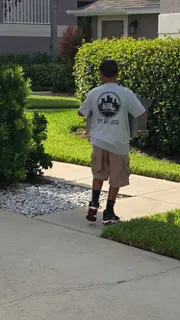 A man is walking down a sidewalk carrying a box.