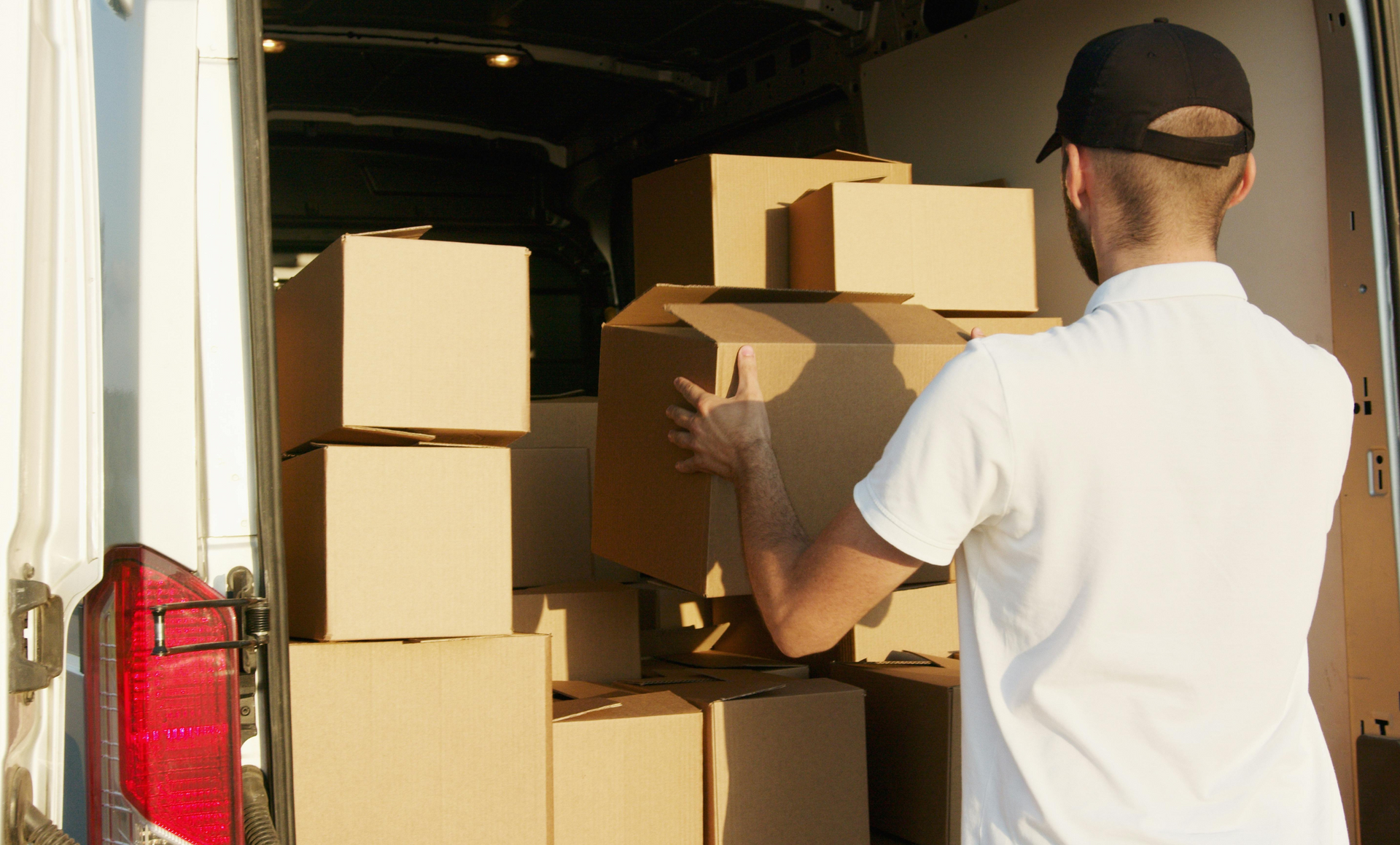 Two movers are carrying boxes out of a van.
