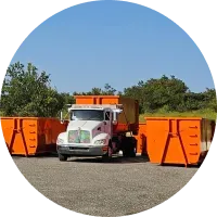 A dump truck is parked in a parking lot next to orange dumpsters.