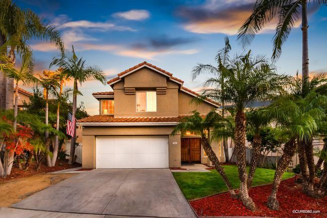 A house with a garage and palm trees in front of it
