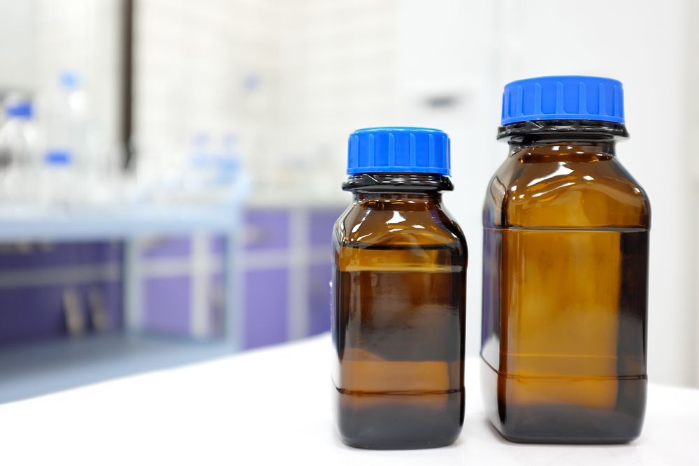 two glass bottles in a lab setting filled with Propylene Glycol Methyl Ether Acetate