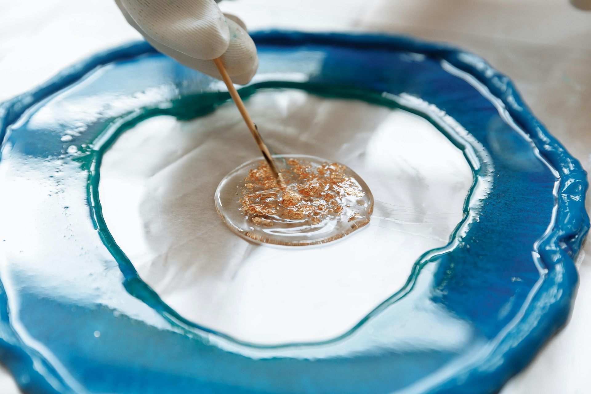A person is pouring liquid on a blue plate.