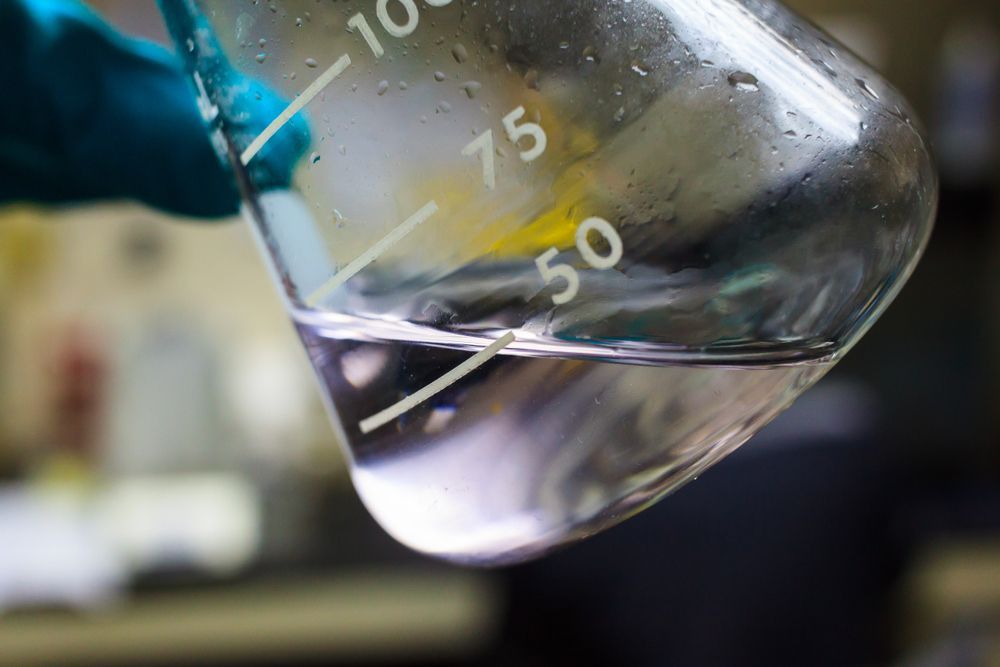 A person is holding a beaker with liquid in it.