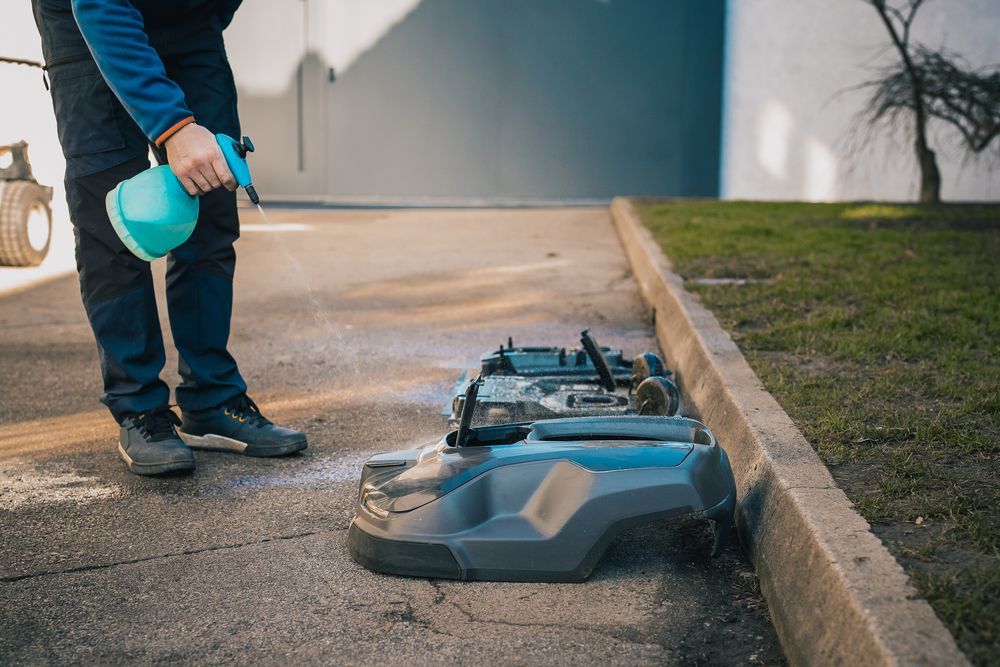 man using a green Xylene solvent spray to clean underneath his lawnmower