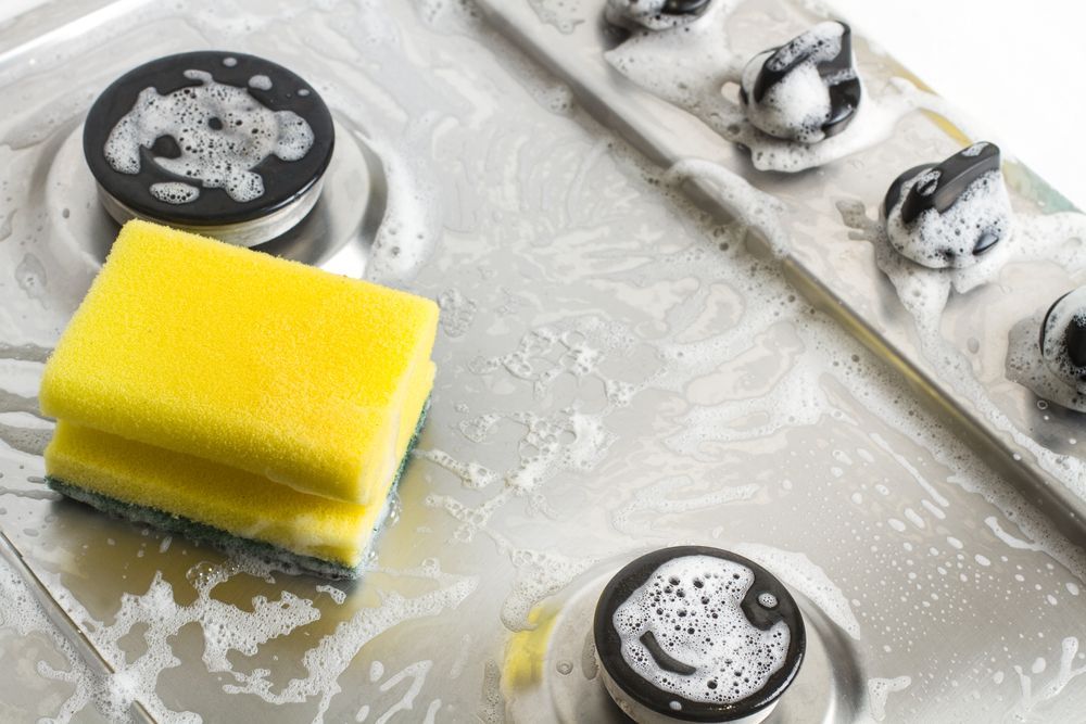 a sponge with solvent degreaser to clean a dirty stove top