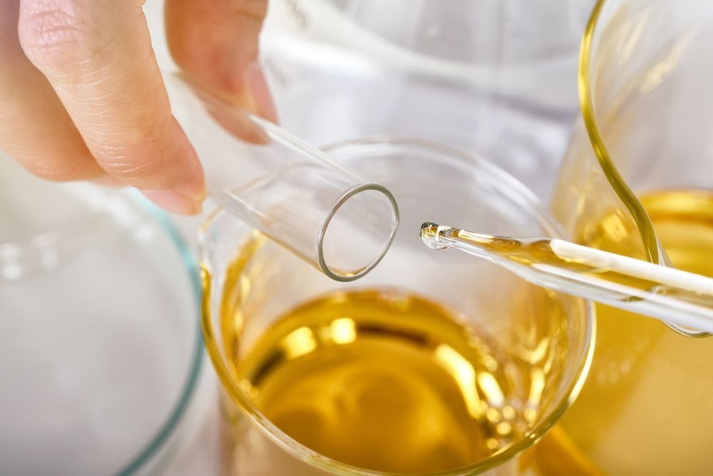 A person is pouring liquid into a glass with a pipette.