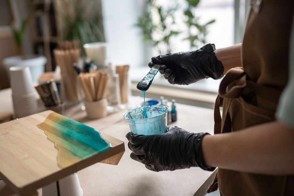 A person is mixing resin on a wooden board.