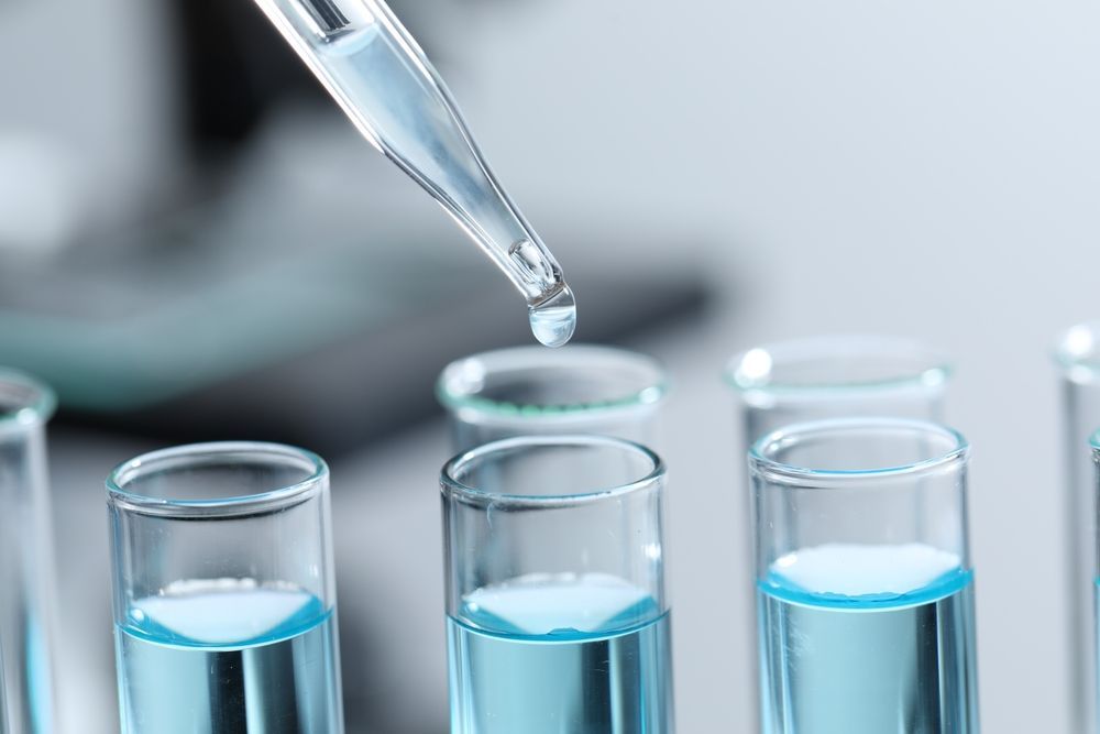 A drop of liquid is being poured into a test tube.